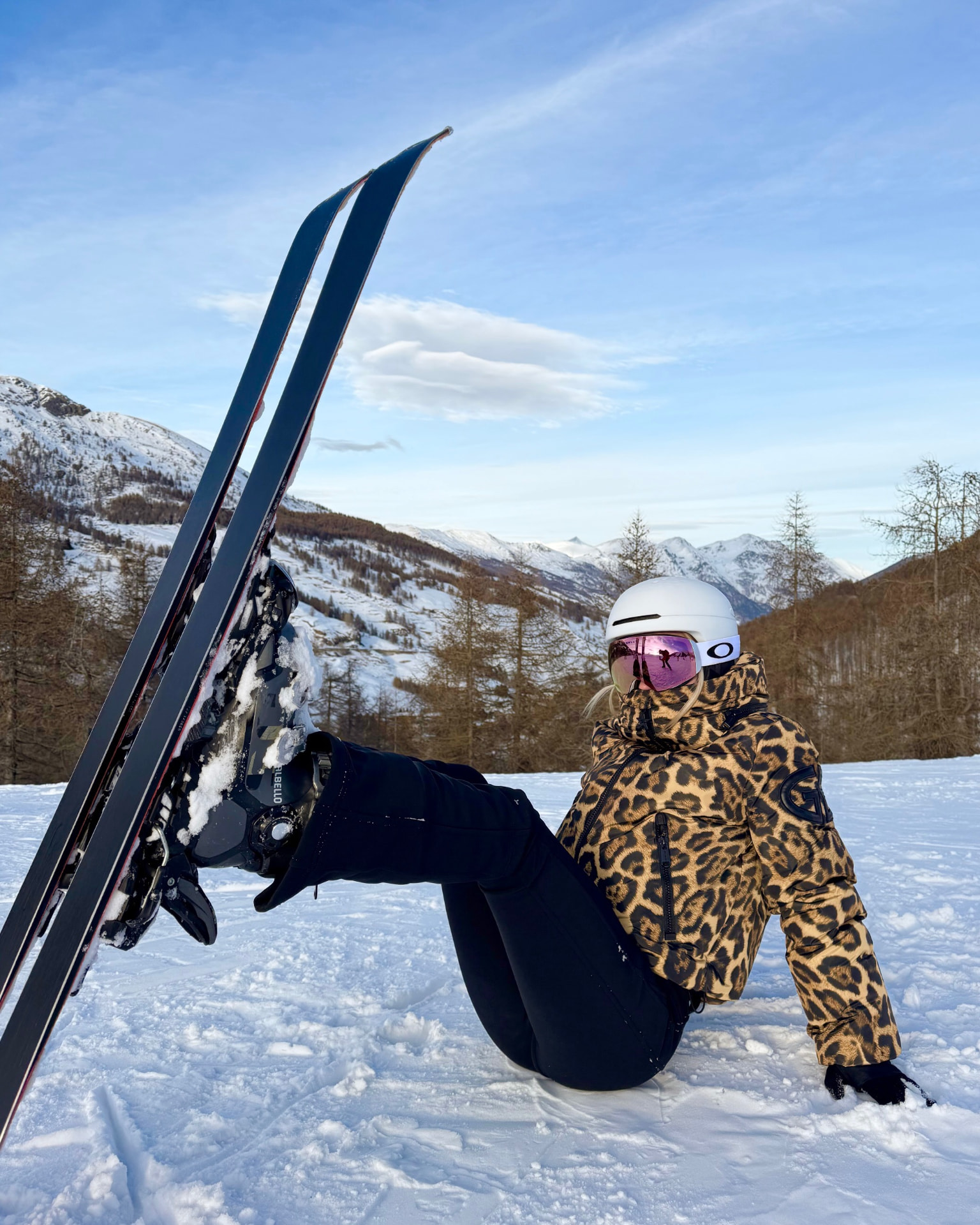 Bronagh sitting in the snow with skis and mountain views